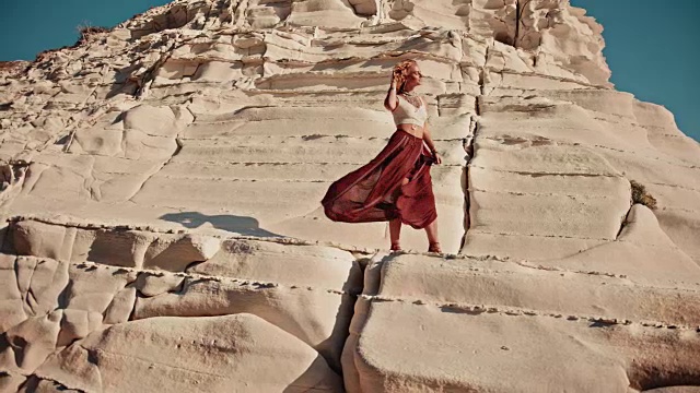 年轻的嬉皮女人站在白山岩石上视频素材
