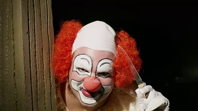 令人毛骨悚然的小丑盯着黑暗的角落用刀抚摸头发/犹他州雪松山，美国视频素材