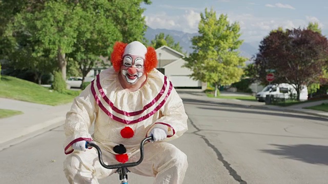 小丑骑着笨拙的小自行车在社区街道/雪松山，美国犹他州视频下载