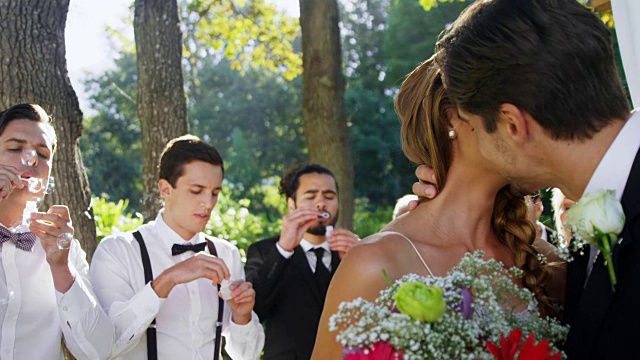 新娘和新郎在后台互相亲吻，客人吹着4K 4K的泡泡视频素材