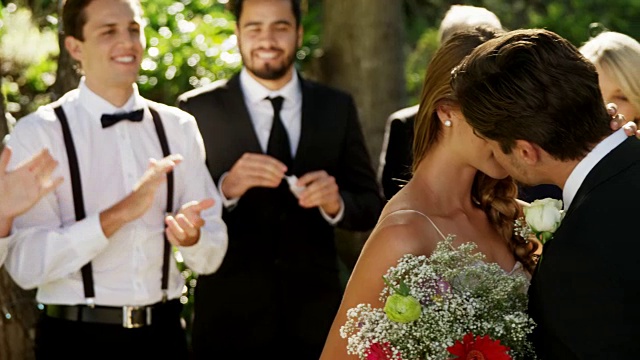 新娘和新郎互相亲吻，客人们鼓掌在背景4K 4K视频素材