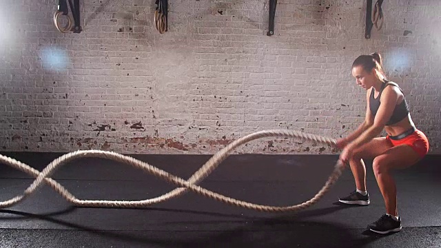 运动的年轻女子在室内用绳子做体操。慢动作视频素材