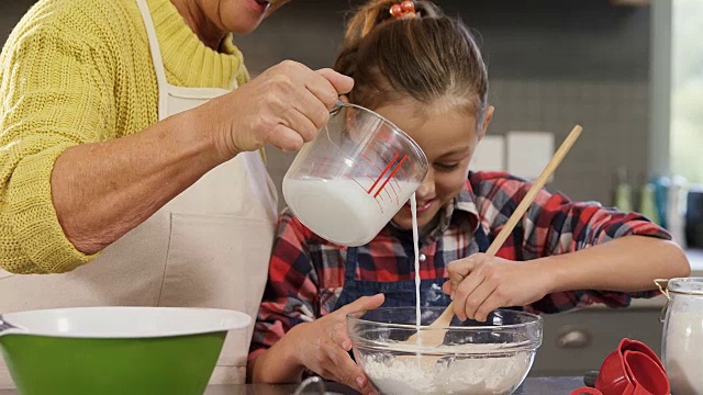 女孩在搅拌面粉，奶奶把牛奶倒进碗里4K 4K视频素材