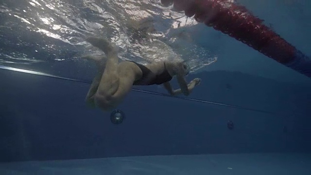 年轻女子浮动蛙泳在游泳池水下视图视频素材