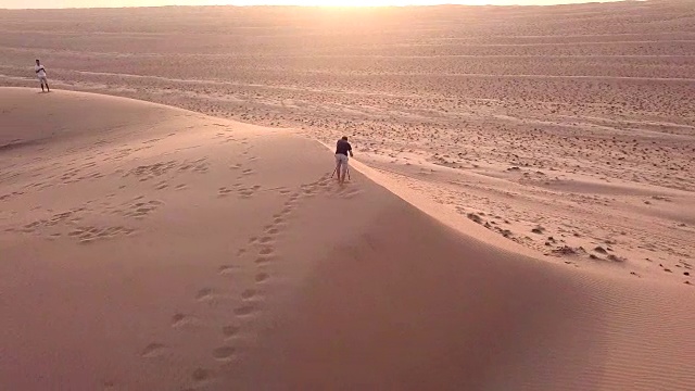 鸟瞰图上的摄影师在沙丘上在沙漠日落视频下载
