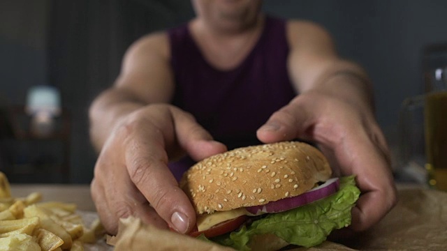 超重的人咬大汉堡，晚上暴饮暴食，肥胖视频素材