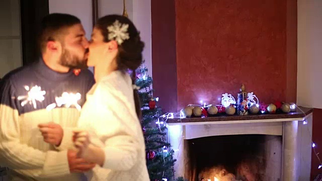 年轻夫妇在家里的圣诞树和壁炉旁庆祝圣诞节视频素材