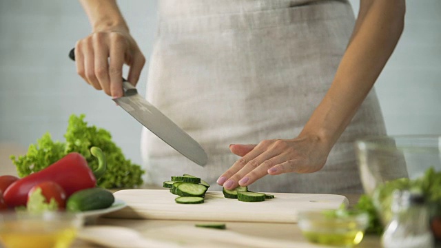女厨师用刀在木板上切新鲜的黄瓜、蔬菜视频素材