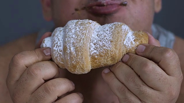 特写的超重男子享受一个牛角面包，暴食作为精神问题视频素材
