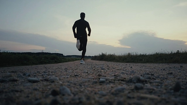 运动员跑向乡村日落全景。自由。背面看安静的秋天路。稳定的镜头视频素材