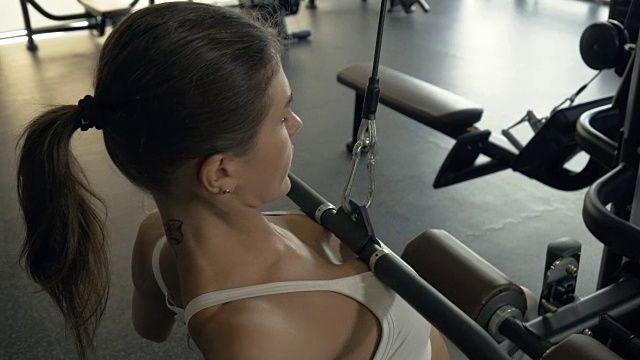 女运动员在健身俱乐部的健身器材上举重视频素材