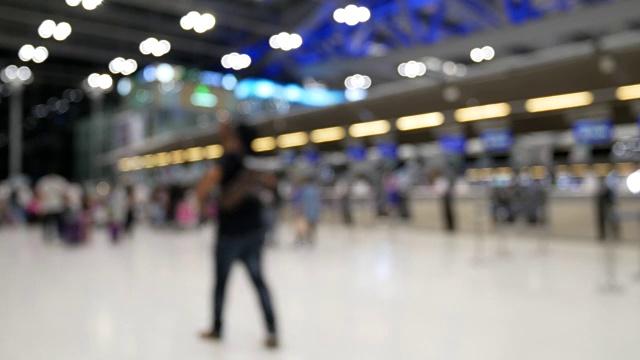 背景:旅客在机场值机柜台前行走的模糊图像。视频素材