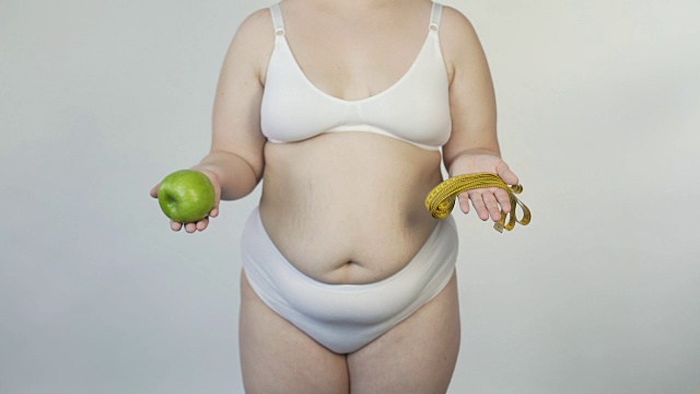身材丰满的女士在镜头前展示胶带和苹果，提出减肥视频下载