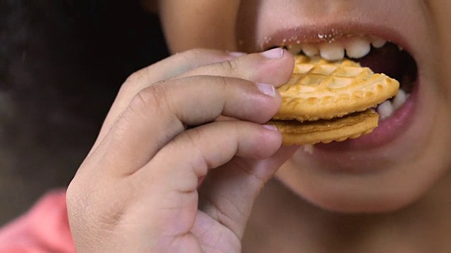特写的孩子吃美味的脆饼干，许多碎屑在小孩子的嘴唇上视频素材