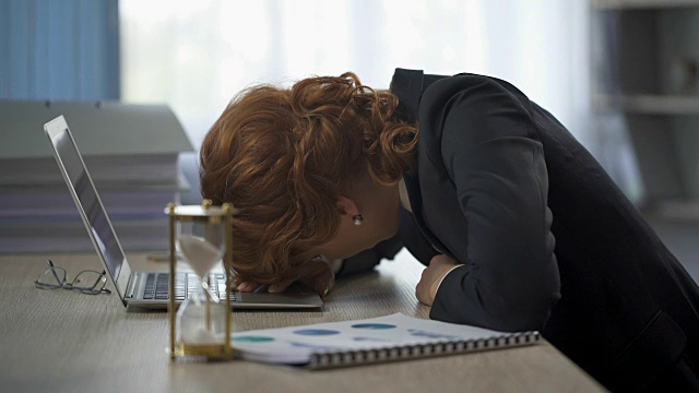 女商人躺在桌子上看着笔记本电脑，疲惫不堪，工作压力大视频下载