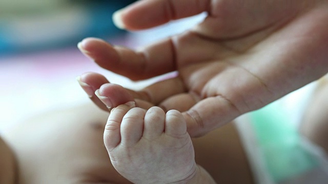 母亲和婴儿的手特写，手牵手。妈妈护理视频素材