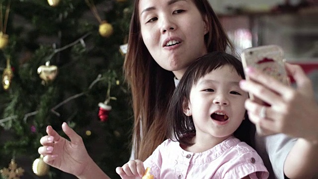 年轻的母亲和女婴使用智能手机和享受在圣诞节视频素材
