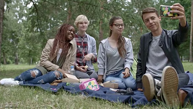 愉快的青少年在野餐时用智能手机自拍视频素材