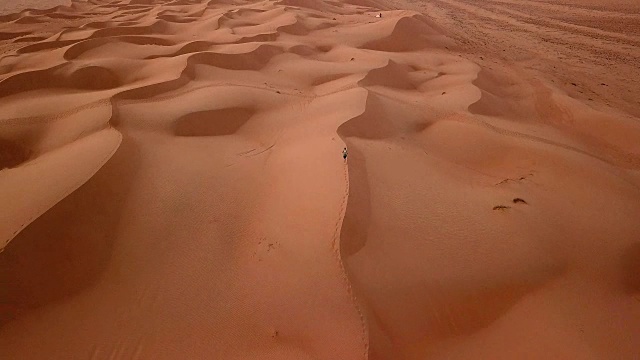 鸟瞰图的男性跑过沙丘在沙漠日出视频下载
