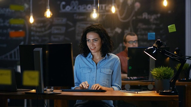 美丽的女职员在她的办公桌上用个人电脑工作。创意办公室的后台同事。视频下载