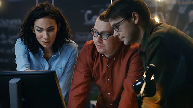 三个办公室员工讨论正在进行的项目，他们指着个人电脑屏幕。他们在创意办公室工作。视频素材