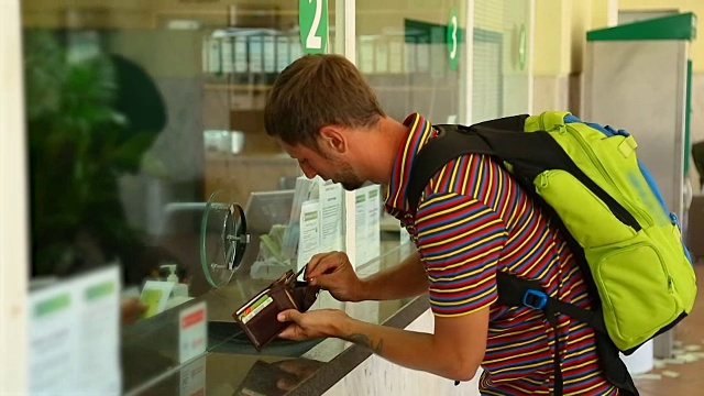 游客在车站收银台搜寻钱包内的钱买票视频素材
