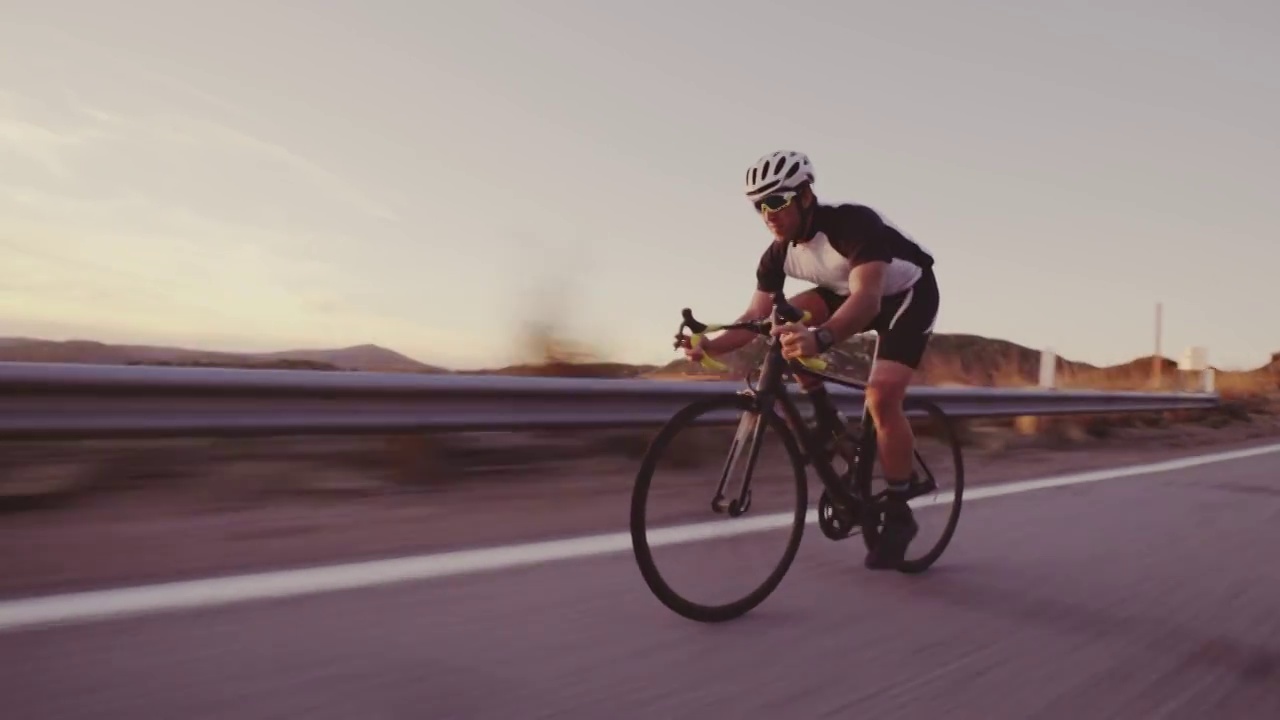 年轻的健康男子在公路上骑自行车，在户外在日落下山比赛视频素材