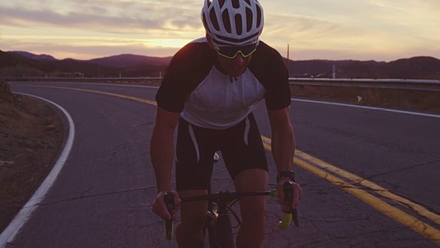 慢动作戏剧性的健身男子锻炼在公路自行车骑上山在日落视频素材