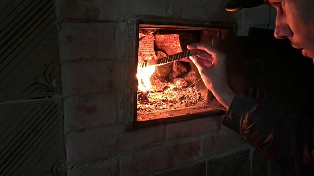 炉子点火。一个男人在炉子里生火。他拿起一块木片，用火搅拌。视频下载