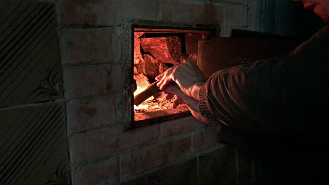 炉子点火。一个男人在炉子里生火。他点燃一块橡胶，把它放在炉子里当柴烧。视频素材