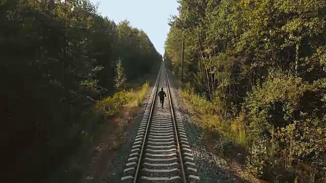 人们在铁轨之间奔跑。无人机的后视图。运动员奔向秋林铁路的新视角视频素材