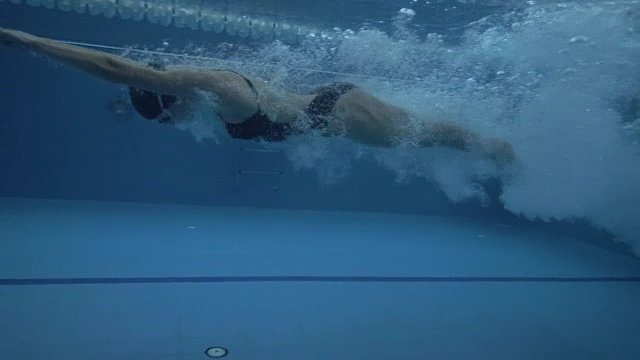 女子跳跃在透明的水在浮动池下的水下观看60帧/秒视频素材