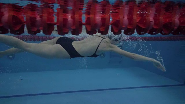 女子游泳运动员在透明水池中以每秒钟60秒的速度在小路上自由泳视频素材
