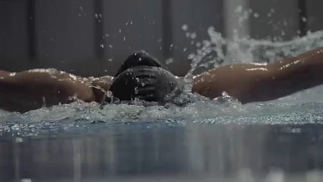健身女子漂浮蝶泳在透明的水池前视图视频素材