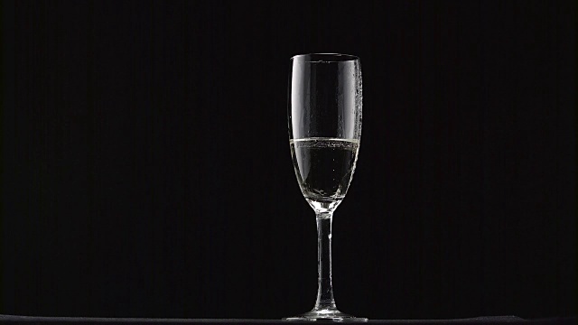 将香槟酒倒入有雾的细柄酒杯中。黑色背景视频素材
