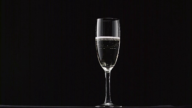 香槟与泡沫倒在一个经典的玻璃上的黑色背景视频下载
