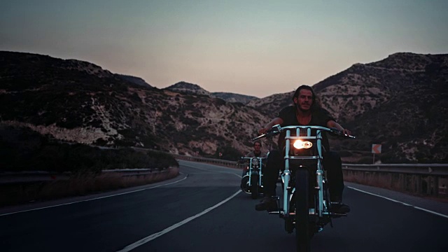 年轻的反叛男子骑着摩托车在山路上旅行视频素材