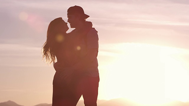 情侣拥抱在日落时，他们亲吻视频素材