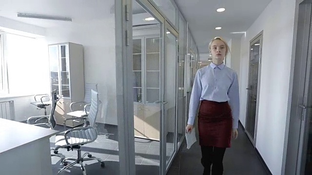 年轻的女商人正穿过现代化明亮办公室的走廊视频素材
