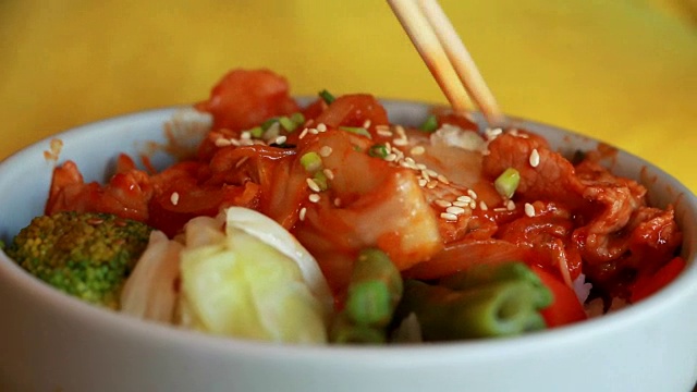 这名男子用筷子夹着陶瓷碗吃着传统的韩国卷心菜、泡菜和猪肉。视频素材