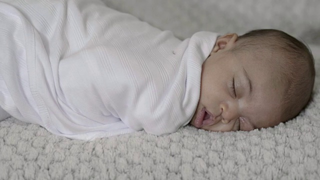 一个婴儿被裹在毯子里打盹的特写滑动镜头视频素材