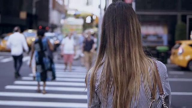 后视图的年轻时尚的女人走在市中心，女性过马路，穿过人群在纽约视频素材