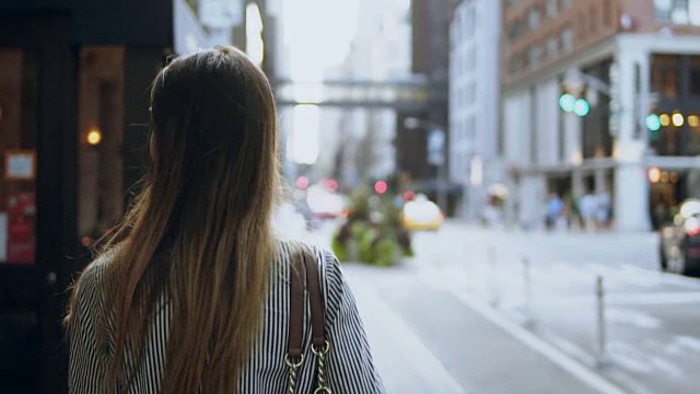 背影年轻的黑发女人走过纽约的街道，美国。头发随风摆动。慢动作视频素材
