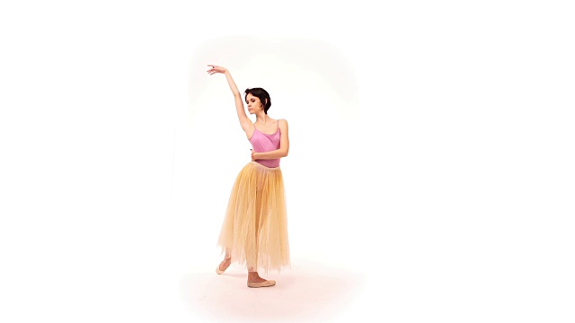 一个年轻的芭蕾舞演员在一个白色的背景下，在工作室里旋转并表演一种被称为“巴蒂特tendus”的舞蹈技巧视频下载