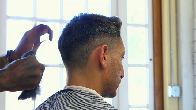 理发师在剪完头发后用刷子给头发最后一抹润色视频素材