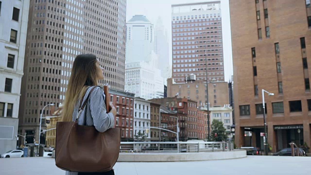 年轻漂亮的女人穿过美国纽约的金融区去上班。慢动作视频素材