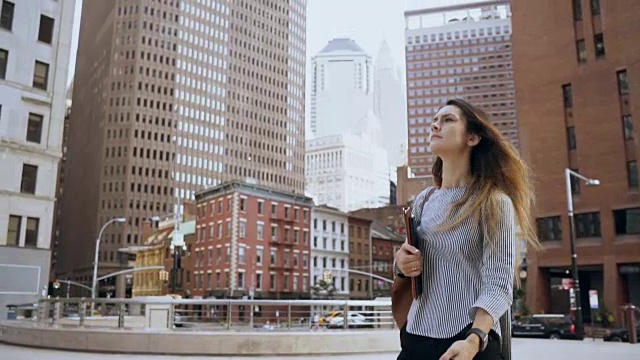 年轻美丽的女商人走在美国纽约的金融区，看着。慢动作视频素材
