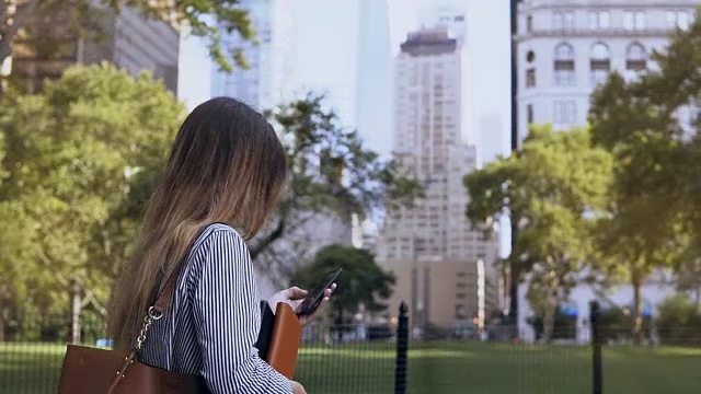 在美国纽约，年轻忙碌的女商人拿着文件用智能手机去上班视频素材