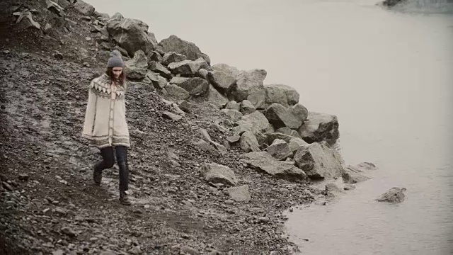 年轻快乐的女人走在冰礁湖的岸边。游客在lopapeysa探索冰岛的风景视频素材