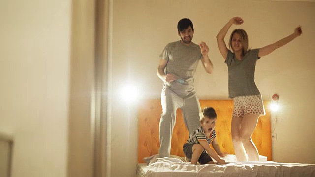 快乐的家庭和小儿子跳舞，在晚上睡觉前在家里的床上玩视频素材
